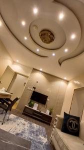 a living room with a ceiling with a tv and a couch at لانا العلا شقق مفروشة Lana Alula in Al-ʿUla