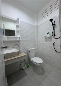 a white bathroom with a toilet and a sink at Palai House in Ban Na Bon