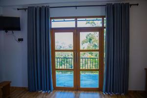 a large window with blue curtains in a room at Tunnel Top Inn Ella in Ella