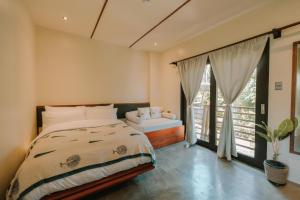 een slaapkamer met een bed en een groot raam bij UNLTD Hotel Siargao in General Luna