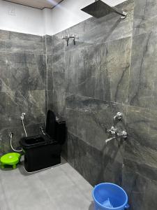 a bathroom with a black toilet and a shower at Prabh palace in Ayodhya
