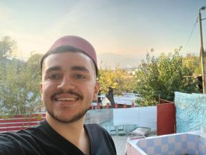 a man with a hat on his head smiling at River BPR Hostel in Tbilisi City