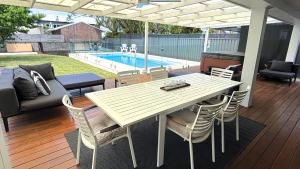 een terras met een tafel en stoelen en een zwembad bij 35 South in Vincentia