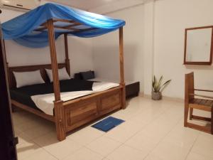 a bedroom with a wooden bed with a blue canopy at Urenium Matara in Matara