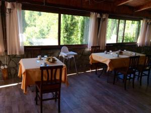 a dining room with two tables and chairs and windows at Masseria degli Alberti in Mormanno