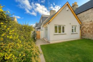 een wit huis met een groen gazon ervoor bij Beachy Days and Family Stays in Nairn