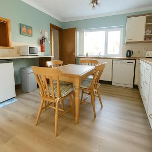 een keuken met een houten eettafel en stoelen bij Beachy Days and Family Stays in Nairn