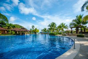 a swimming pool at a resort with palm trees at Vista Bahia 3C 3 bdr Ocean View in Los Suenos in Herradura