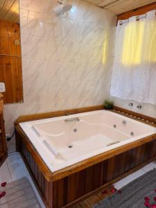 a large white tub in a bathroom with a window at Suíte Rustica Aconchego - Com Banheira de Hidromassagem in Campos do Jordão +37 photos
