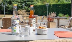 twee flessen bier en glazen op een tafel bij Brit Hotel Agen - L'Aquitaine in Le Passage