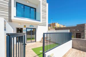 een huis met een balkon met een zwarte poort bij MEDANO4YOU The Surf Backyard in El Médano