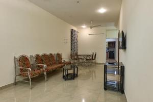 Immanuel Homestay, Kalathipady, Kottayam, Flat E في كوتايم: غرفة معيشة مع كراسي وطاولة وأريكة