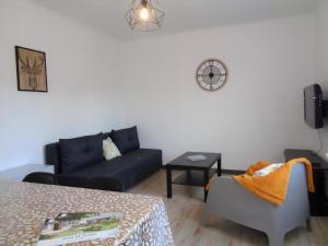 a living room with a couch and a chair and a clock at Le sorberan in Sorbiers