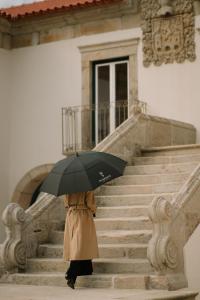 Una persona subiendo unas escaleras con un paraguas en The Vinea Collection Hotel by Piamonte Hotels, en Monção