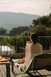 una mujer sentada en una silla con una copa de vino en The Vinea Collection Hotel by Piamonte Hotels, en Monção