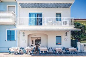 a white building with tables and chairs and a balcony at B&B El Gatt in Marotta