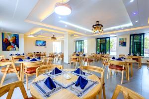 Un restaurante con mesas y sillas de madera y ventanas. en Marikeka Hotel, en Galu
