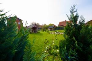a yard with houses in the background with trees at Šv Hubertas in Karklė