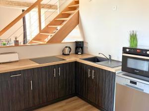 a kitchen with wooden cabinets and a sink and stairs at Les Glaneuses gîte Entre Amis centre-bourg à 3 min du Puy duFou in Les Épesses