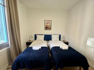 Monaco Villa BRIGITTE Terrasse في بوسولاي: غرفة نوم بسريرين ذات أغطية زرقاء ونافذة