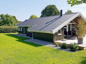 een klein groen huisje met een veranda en een gazon bij 8 person holiday home in Sydals-By Traum in Skovmose