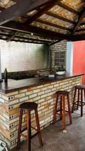 a bar with three wooden stools next to a brick wall at Pousada Solar de Maria e Hostel in Baixa de São Francisco +35 photos