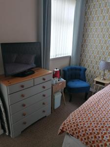 a bedroom with a dresser and a bed and a blue chair at The Kirkview in Blackpool