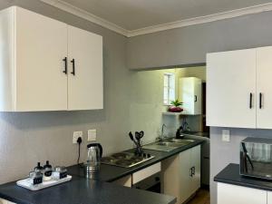 a kitchen with white cabinets and a black counter top at Tana's flat in Brakpan +10 photos