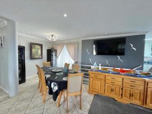 Un comedor con mesa y sillas y un televisor. en Lilies and Leopards Holiday Home B & B, en Mossel Bay
