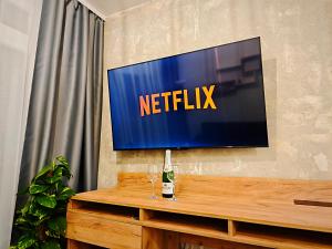 a television on a wall with a bottle and two glasses at Axiom Suites - Zenith II - Netflix, HBO, Champagne in Košice