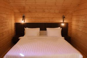 a bedroom with a bed with white sheets and lights at Chalet Myler in Yeghipatrush