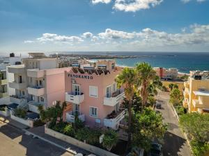 an aerial view of a pink building in front of the ocean at Panoramio Paleochora Apartments in Palaiochóra