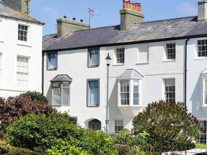 a white house with trees in front of it at Tri Raglan Mawr in Beaumaris