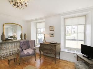 a living room with a chair and a table and a mirror at Tri Raglan Bach in Beaumaris