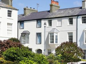 a white house with trees in front of it at Tri Raglan Bach in Beaumaris