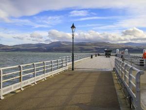 a pier with a street light next to the water at Tri Raglan Bach in Beaumaris +9 photos