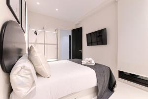 a white bedroom with a bed and a flat screen tv at Apartamento Bilbo in Bilbao