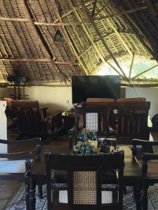 a room with a table and chairs and a television at Lennana Escape in Ukunda