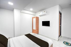 a bedroom with a bed and a tv on the wall at Super Hotel O Sneh Rashmi Botanical Garden Surat Formerly Stadium Plaza in Bhatha +25 photos