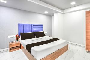 a bedroom with a large bed with a blue headboard at Super Hotel O Sneh Rashmi Botanical Garden Surat Formerly Stadium Plaza in Bhatha