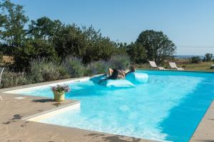 a woman is laying on a blue raft in a swimming pool at Collina Blu - Umbria - Lago di Bolsena in Bolsena