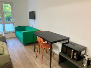 a living room with a table and a green couch at Work&Travel WE13 - Parkplatz, Netflix, Internet für 2 Gäste in Markranstädt +2 photos