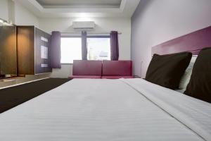 een slaapkamer met een groot bed en paars meubilair bij Super Collection O Paithan Gate Formerly Rajlaxmi Executive in Aurangabad +22 foto's