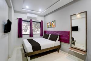 een slaapkamer met een bed met paarse gordijnen en een spiegel bij Super Collection O Paithan Gate Formerly Rajlaxmi Executive in Aurangabad