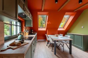 - une cuisine aux murs orange avec une table et des chaises dans l'établissement Willa Bukowy Las - Everslow, à Szklarska Poręba