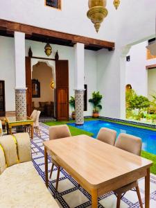 a living room with a table and a swimming pool at Dar Elinor Fez in Fès