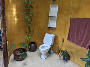 a bathroom with a toilet next to a yellow wall at Why Nam Stunning Beach & Ocean View Jungle Penthouse in Ko Phangan