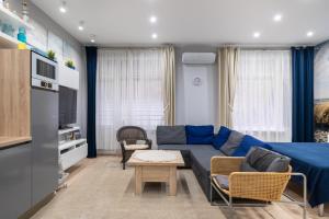 100m to Sea Beachside Studio with Private Garden & Terrace في يورمالا: غرفة معيشة مع أريكة وكراسي زرقاء