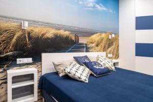 100m to Sea Beachside Studio with Private Garden & Terrace في يورمالا: غرفة نوم بسرير مع لوحة على الشاطئ