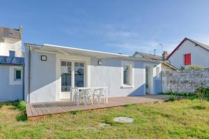 a white house with a table and chairs on a deck at Maisons de Saint Guenolé in Batz-sur-Mer